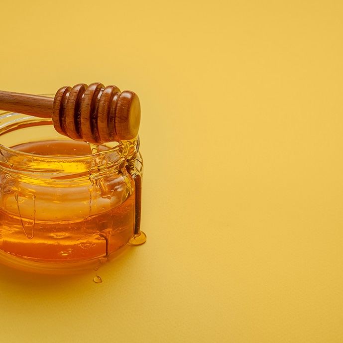 عکس با کیفیت قاشق و ظرف عسل در زمینه زرد