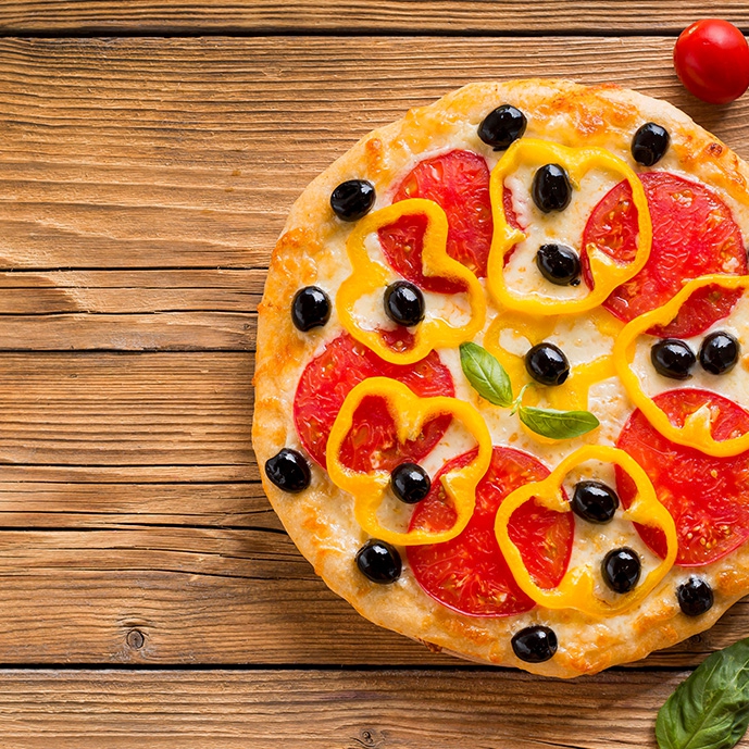 عکس باکیفیت پیتزا با تزئین فلفل دلمه‌ای زرد روی سطح چوبی